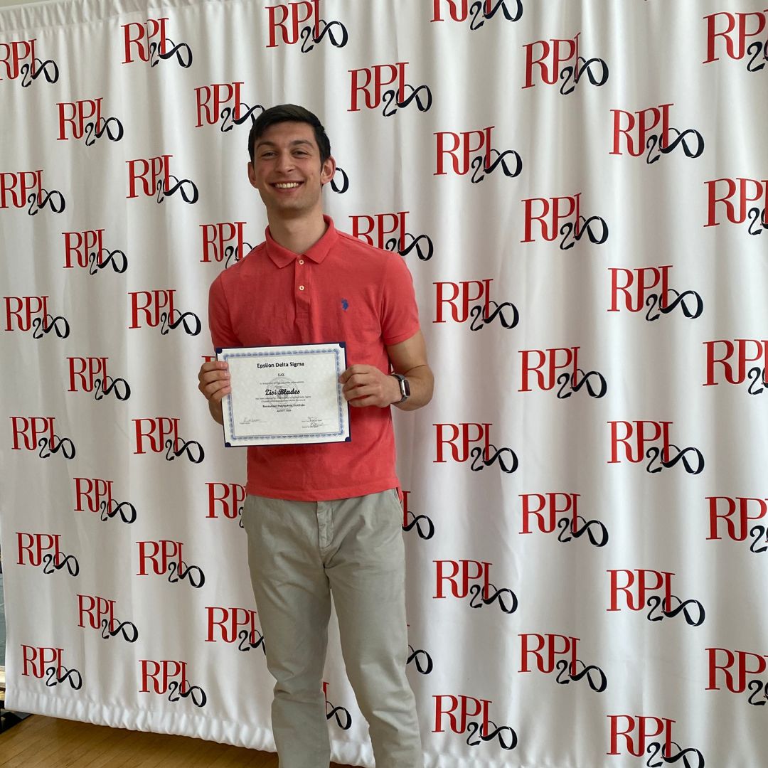 A person stands smiling, holding a certificate in front of a backdrop with the RPI Bicentennial logo repeated.