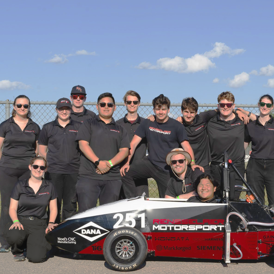 The Rensselaer Motorsport team poses together outdoors with their Formula-style race car