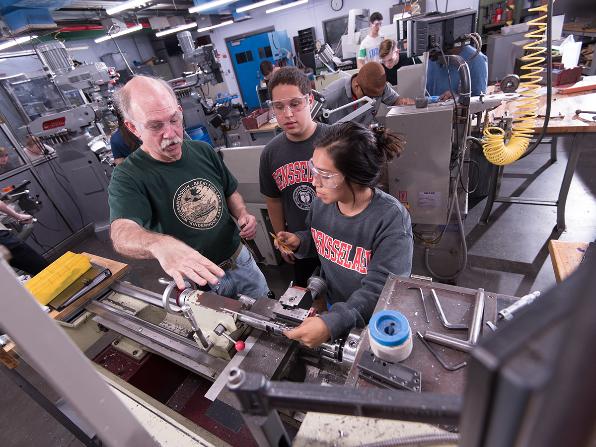 A group of people work with manufacturing equipment