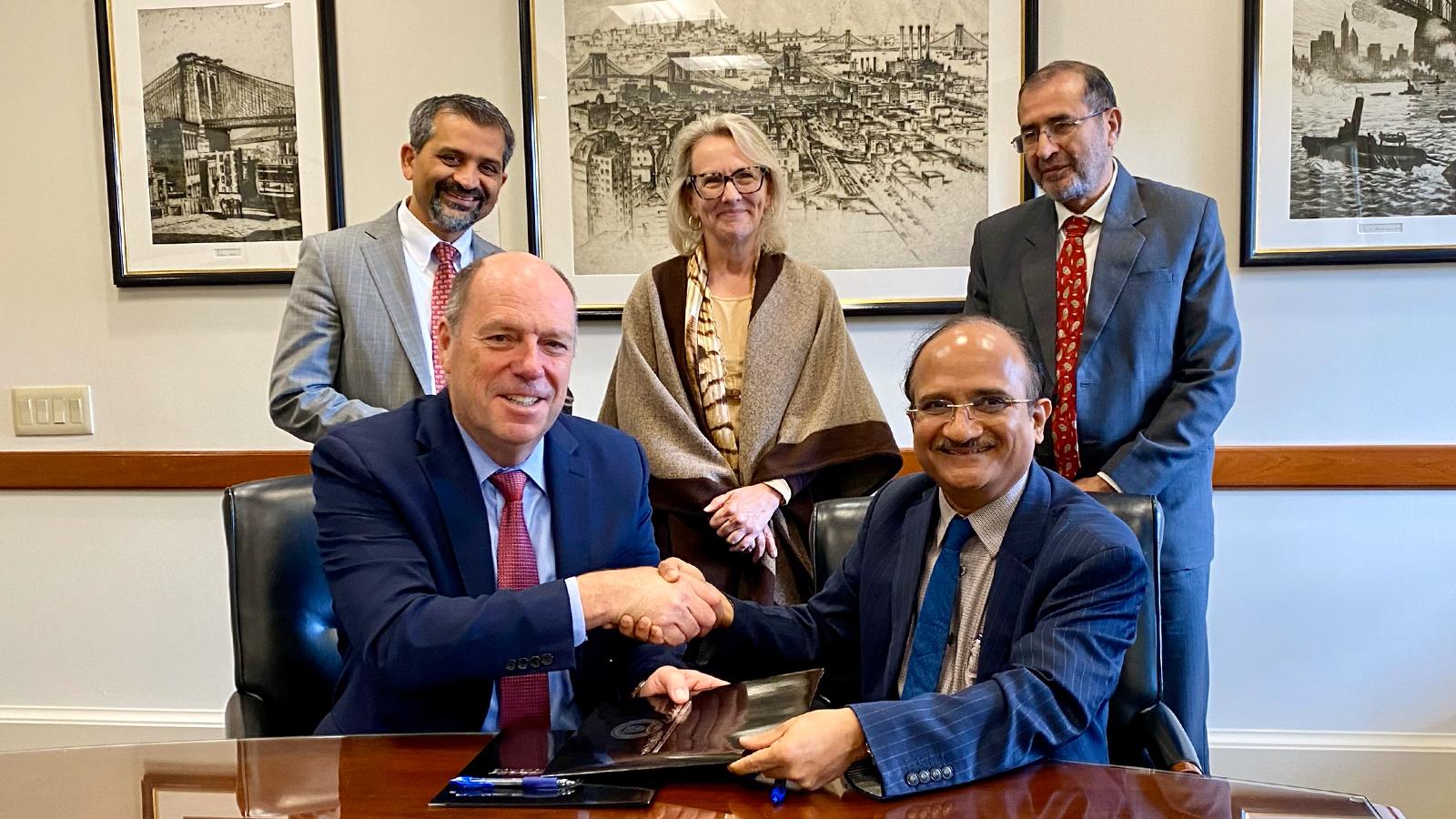 Two people shake hands after signing a document