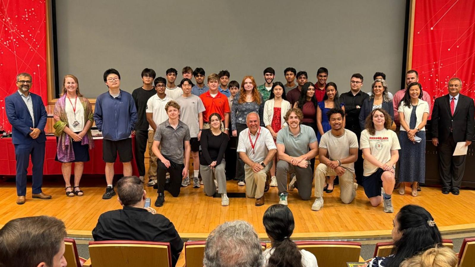 Group of campers and faculty/staff standing together on stage