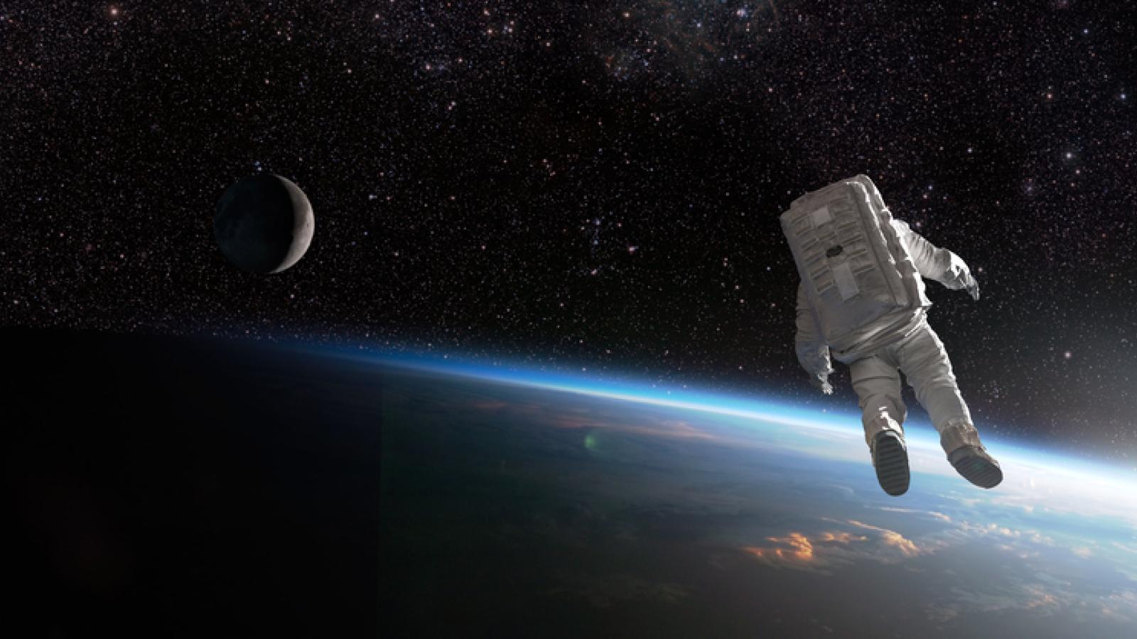 A composite image of an untethered astronaut in rear view, isolated and drifting off into deep space above the earth.