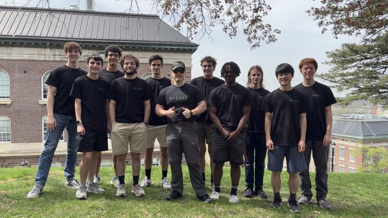 Group of students standing close together, all wearing matching black t-shirts.