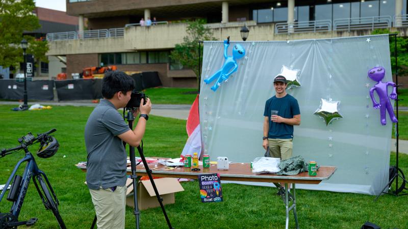 A student takes a photo of another student against a backdrop at Rally Week.