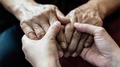 Older person holding hands with younger person