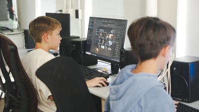 Two individuals are focused on a computer screen displaying a complex software interface 